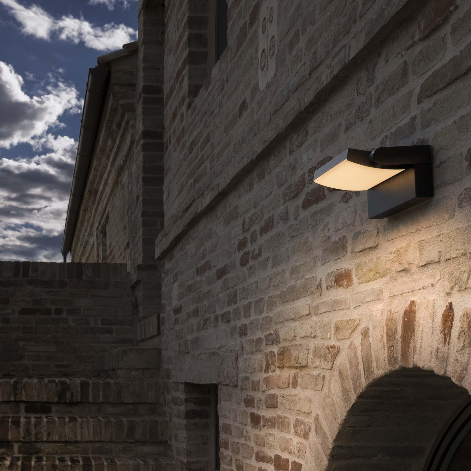 Wandlamp die strijklicht over een bakstenen gevel geeft